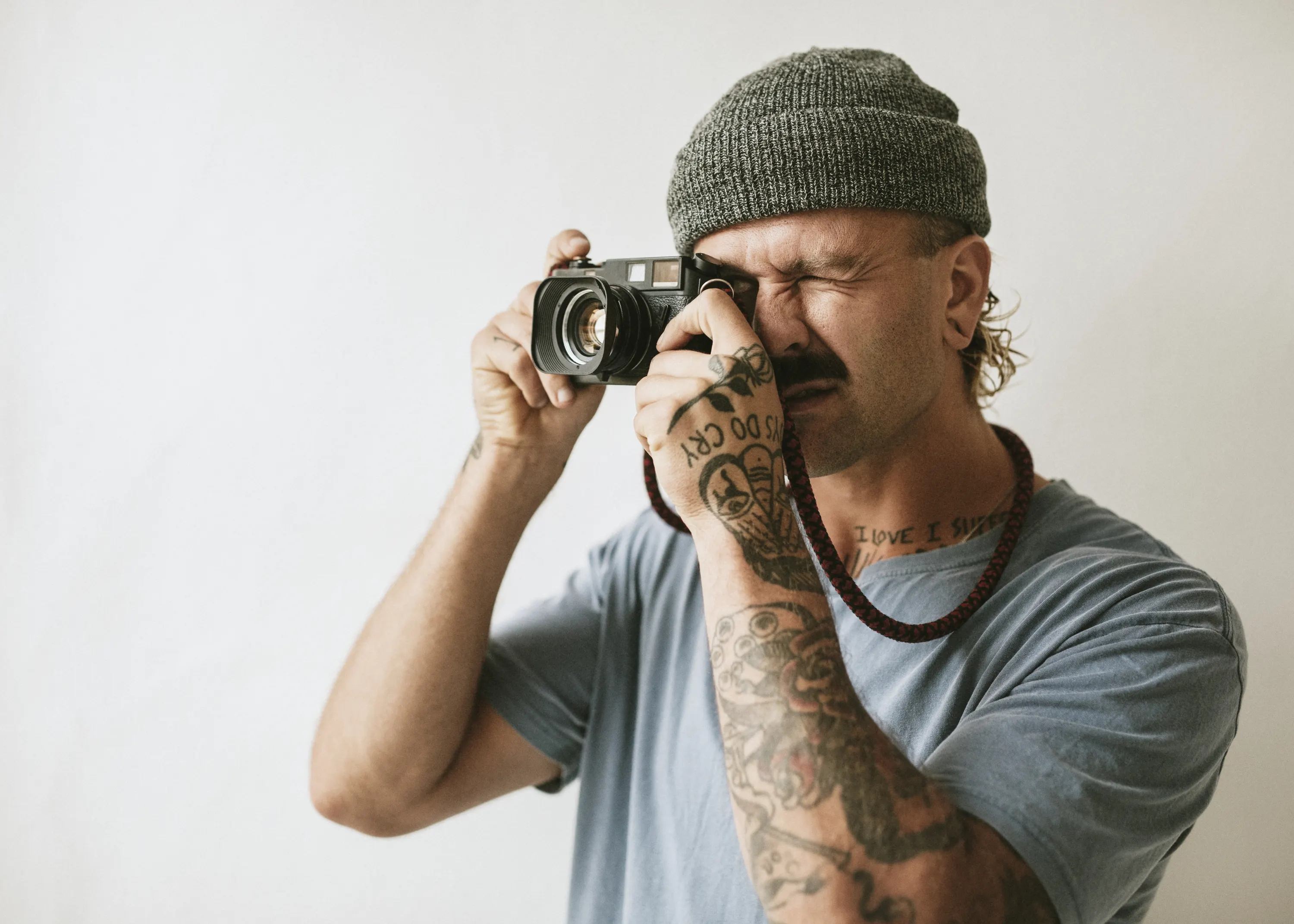 homem tirando foto com câmera num estudio com parede clara