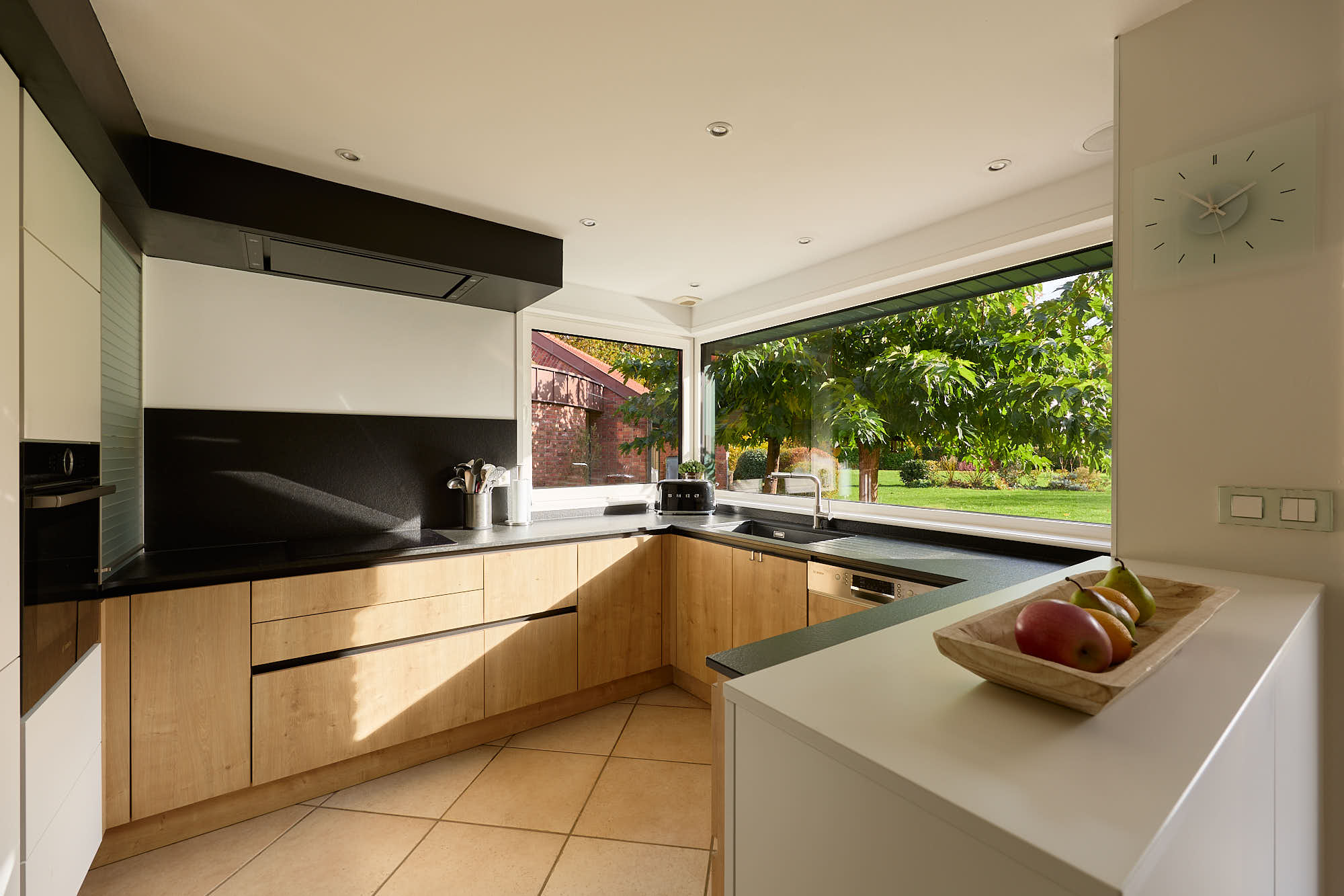 Cuisine moderne tout équipée avec une vue vers un jardin entretenu et vert.