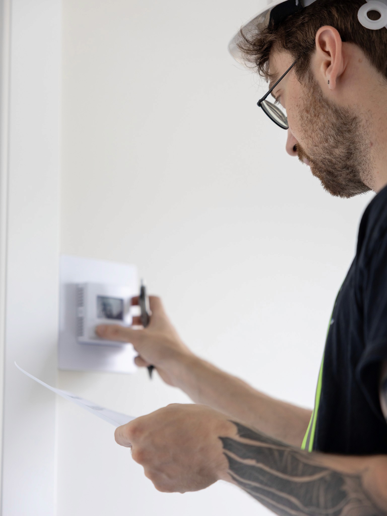 HVAC technician in Kelowna, British Columbia, installing thermostat in Fraser Valley home plumbing system.