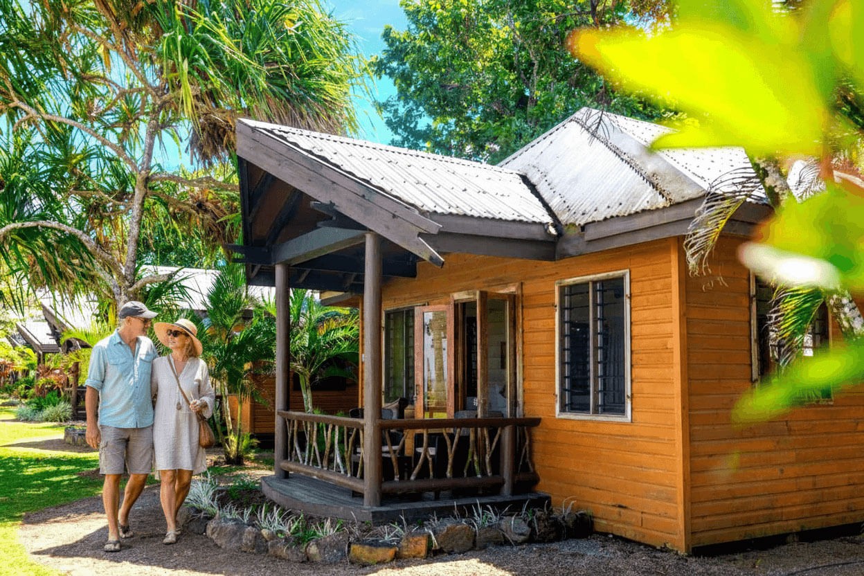 A couple walking back toward their traditional Fijian bure surrounded by lush forest surroundings