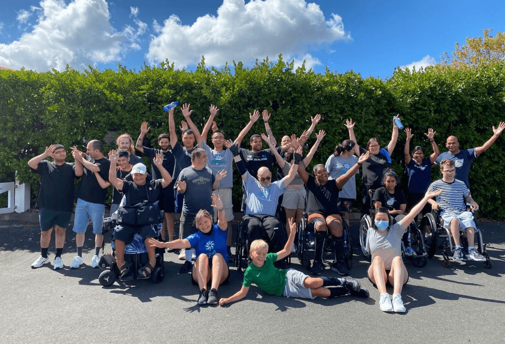 A group of people of all abilities waving their hands and smiling