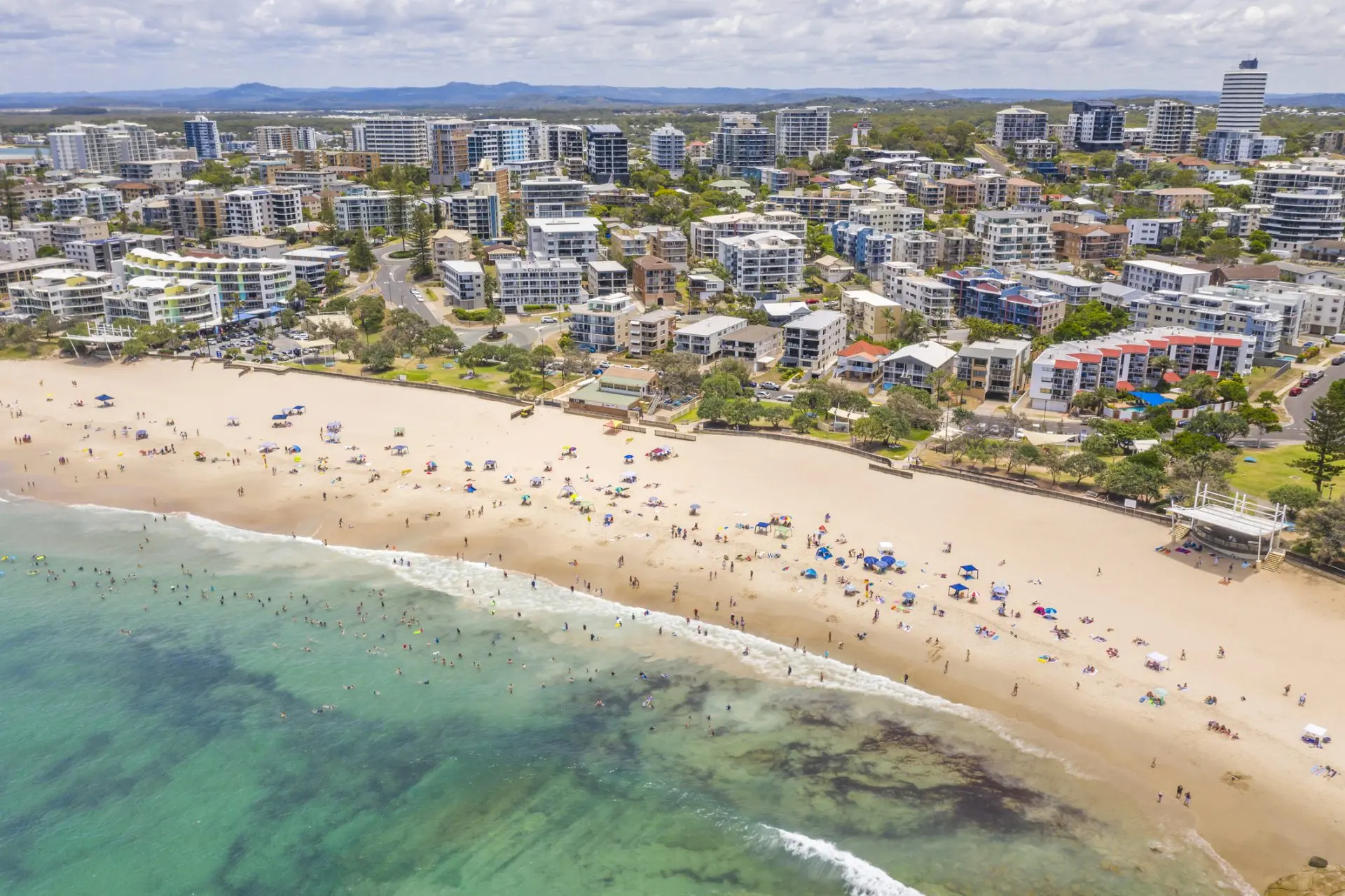 Crowded beach with ocean and city buildings
