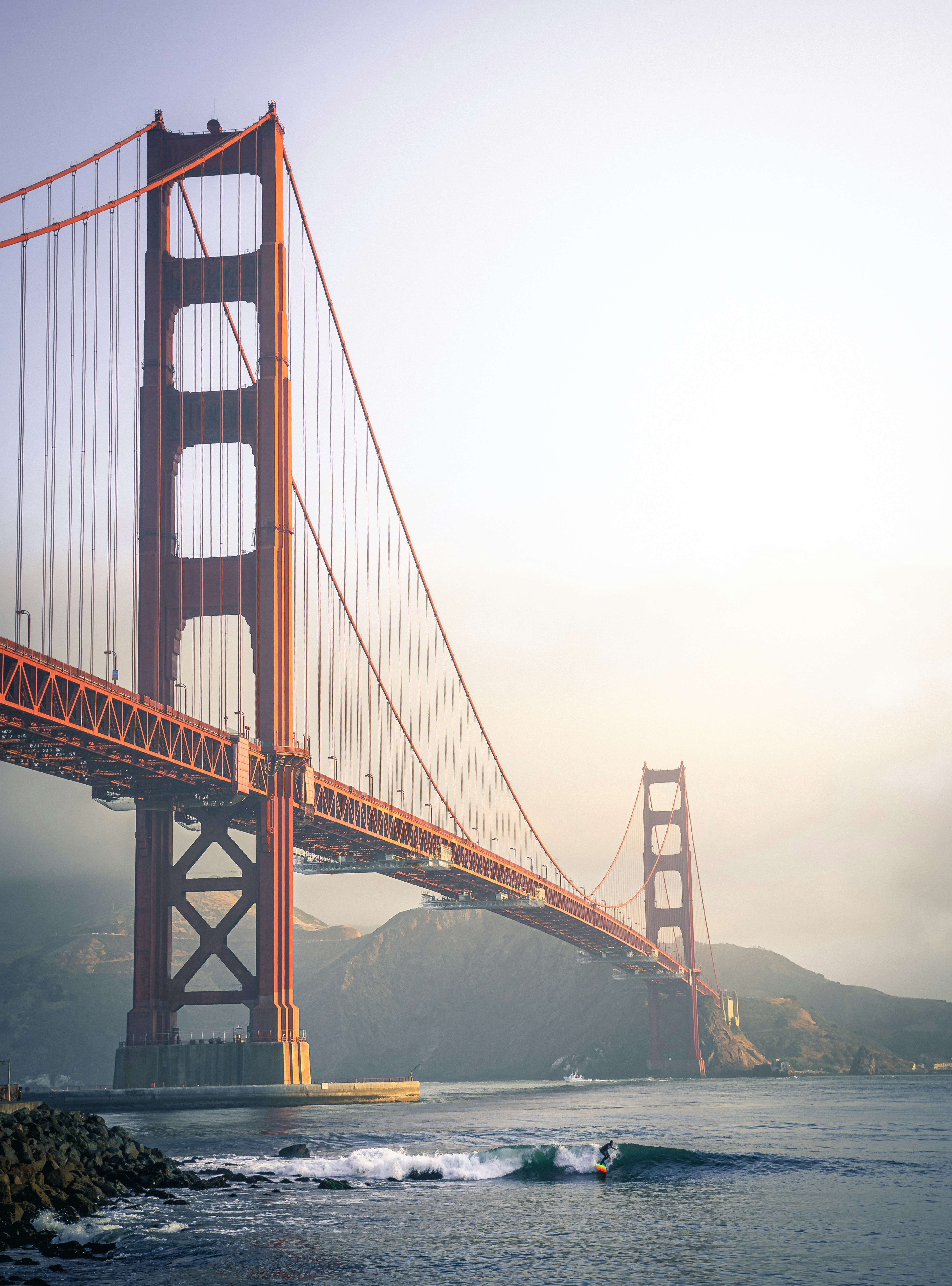A smiling young man with crossed arms, wearing a plaid shirt and white t-shirt, poses against a dark background.