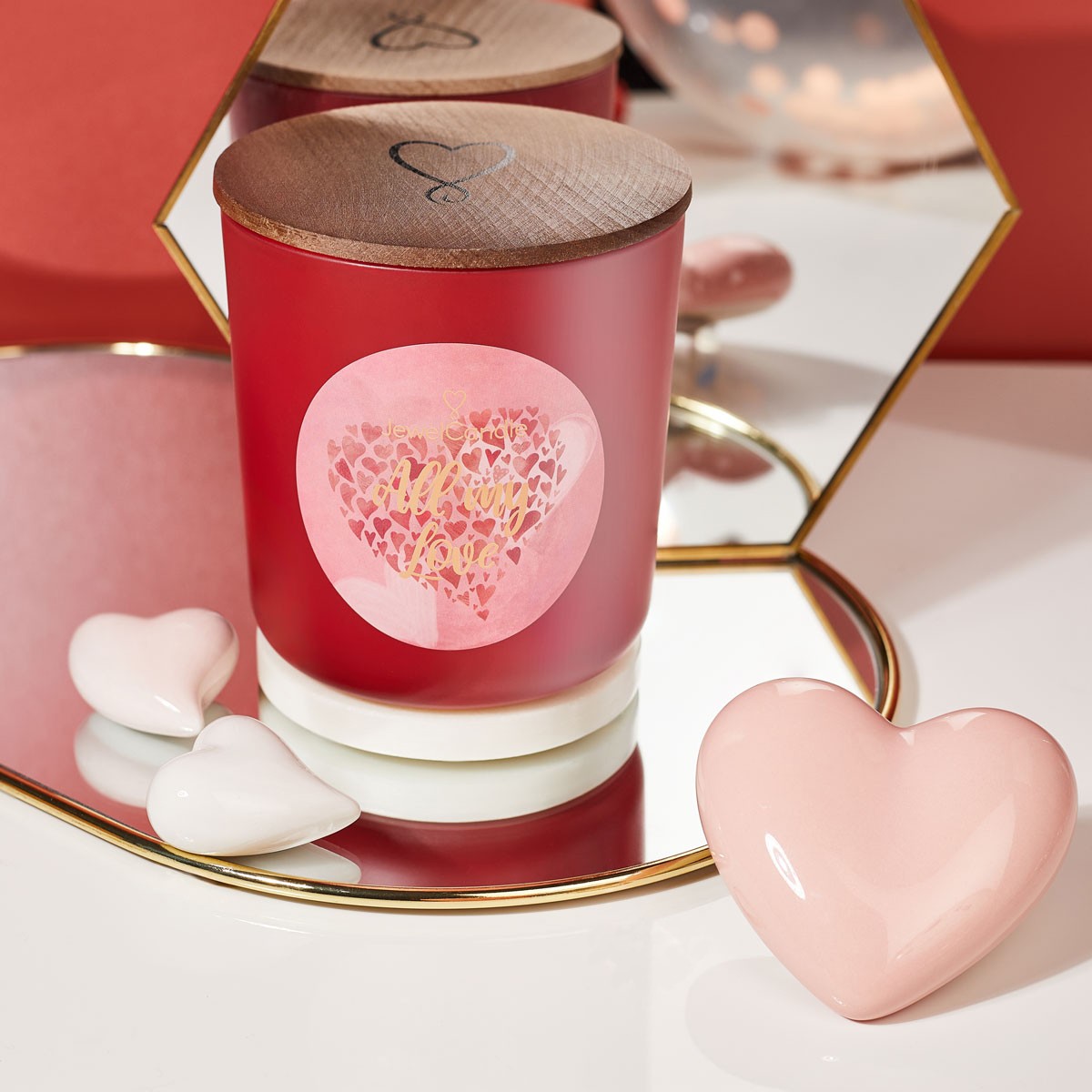 A red candle with a red-pink label showing a heart shape collection of hearts