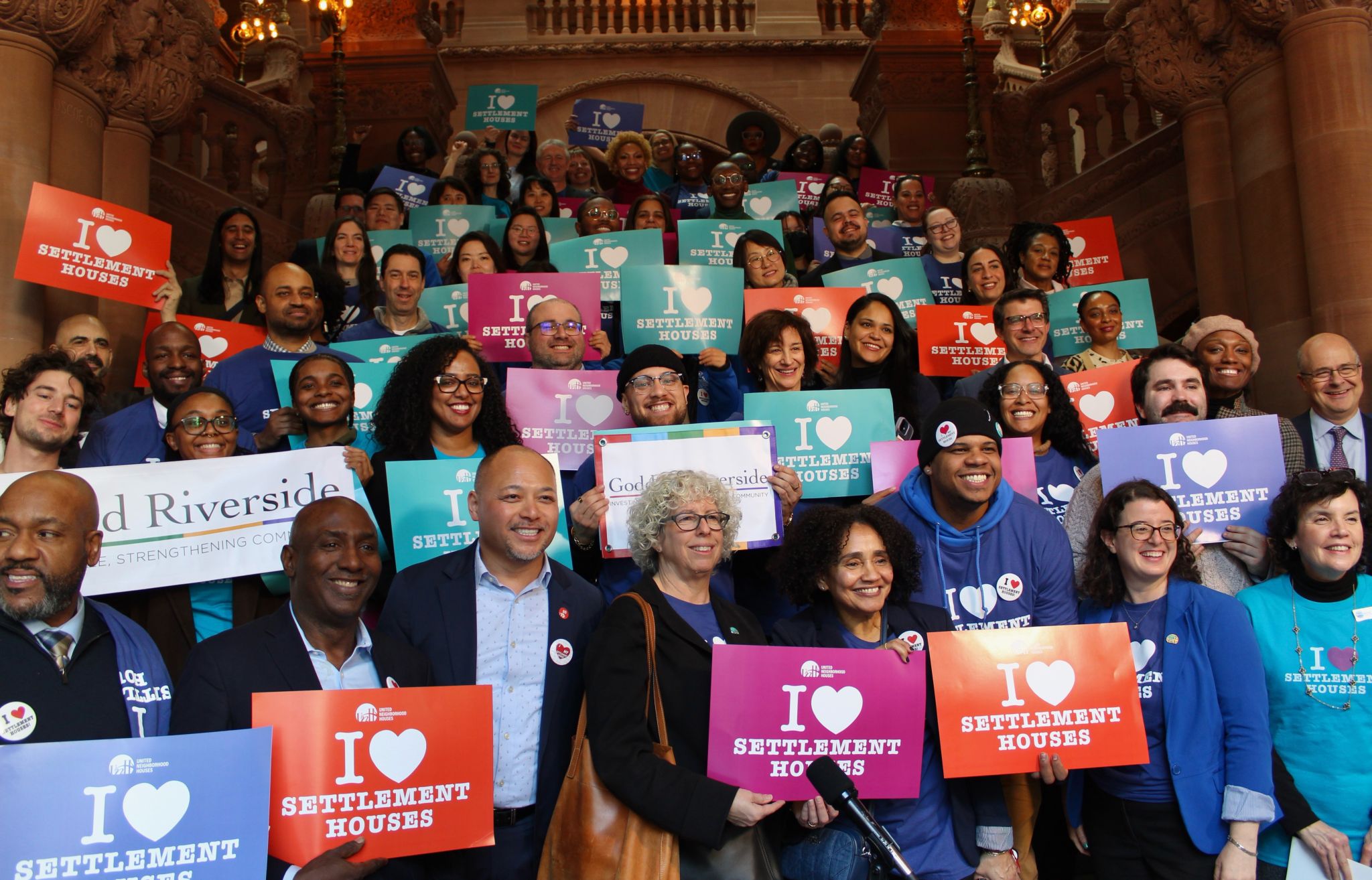 Group photo of Settlement house advocates holding various colorful signs that state "I Heart Settlement Houses"