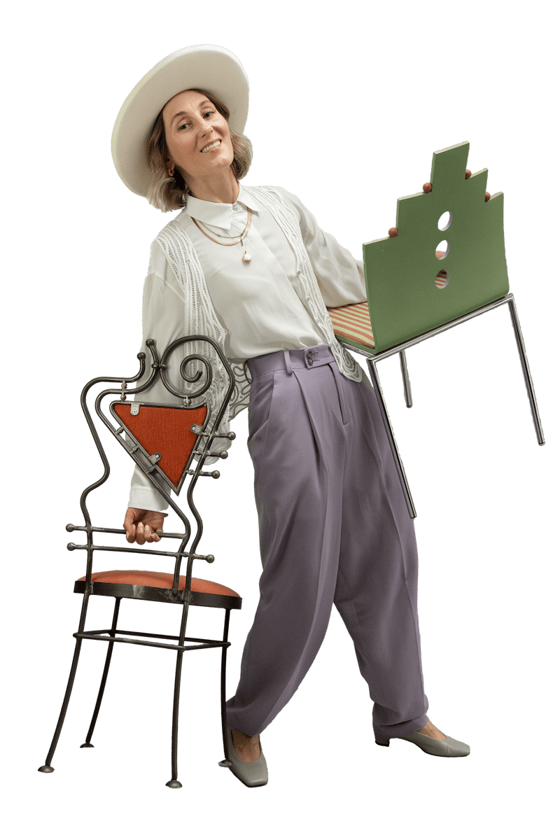 Judith, designer dressed in vintage fashion, holding a metal chair and a green well designed chair.