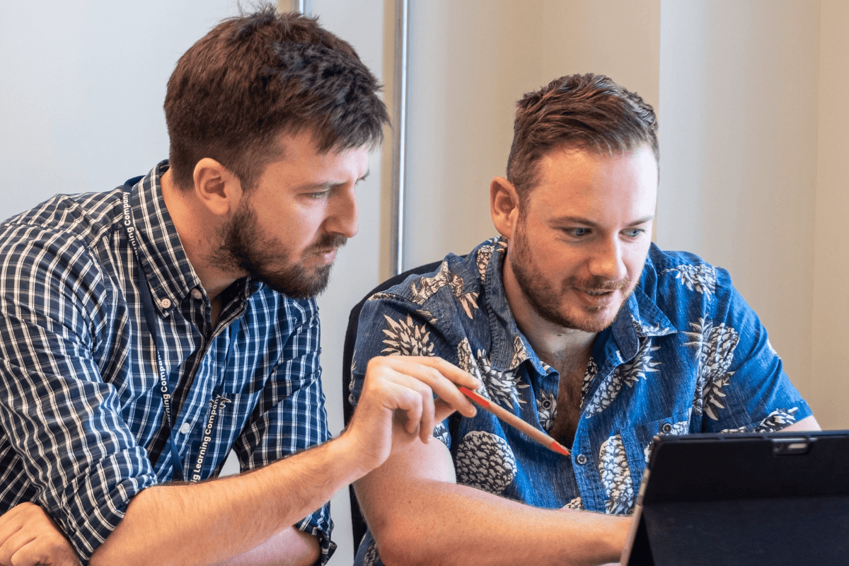 Two people in a room working on something with laptops.