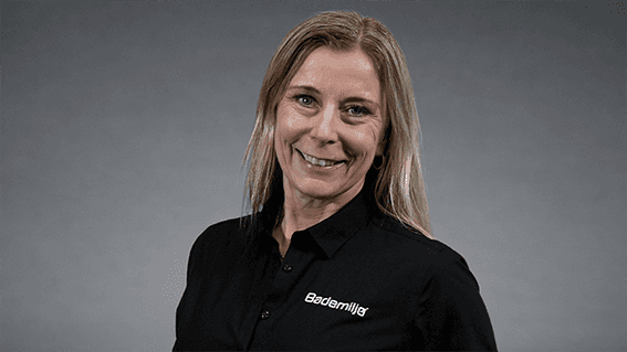 Benedicte Inversini kjededirektør Bademiljø i sort skjorte med Bademiljø logo foran nøytral grå bakgrunn