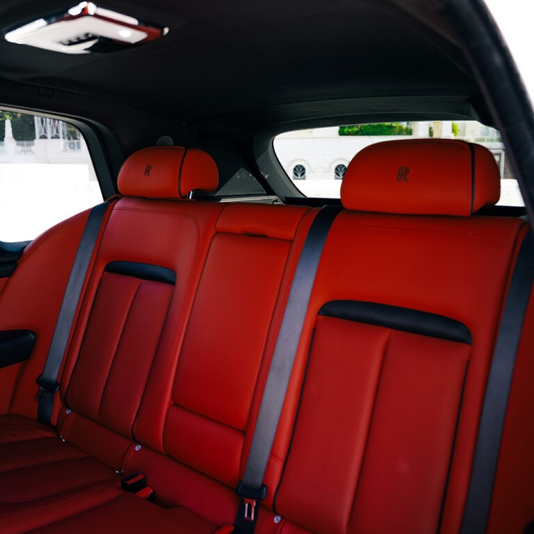 Close-up of Rolls-Royce Cullinan's plush red leather rear seats and interior stitching.