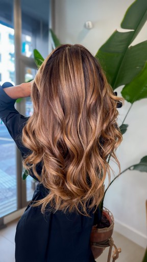 A young woman with wet hair, leaning back in a bath with her eyes closed. The sunlight reflects off the water, creating a serene and tranquil atmosphere.