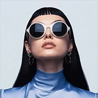 Stylish person in white sunglasses and shiny blue top, exuding modern chic against a neutral backdrop.