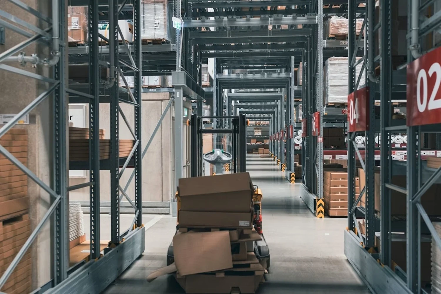 Warehouse storage aisles with pallet racking, inventory and a forklift in a UK logistics facility.
