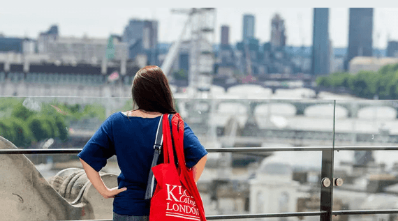 Person looking out at the city with a building and skyscrapers in background.
