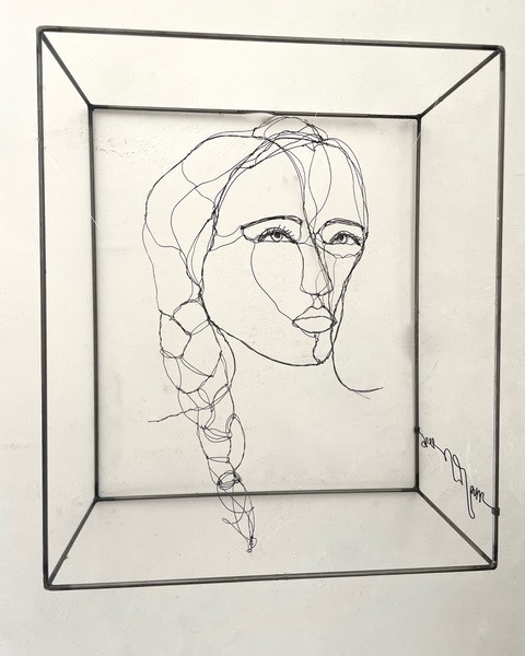 Sculpture en fil de fer représentant le visage d'une femme dans un cadre en fil de fer, vue détaillée de face