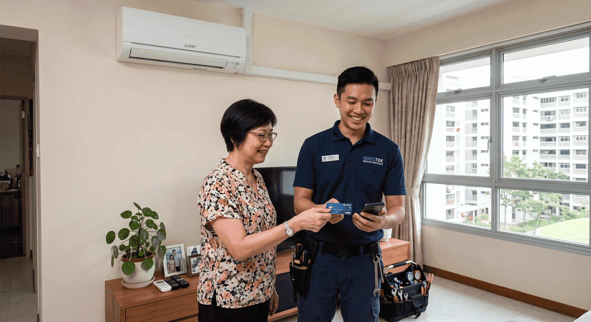 Technician using Tap to Phone on an Android device to process a customer credit card payment after servicing an air conditioner in Singapore.