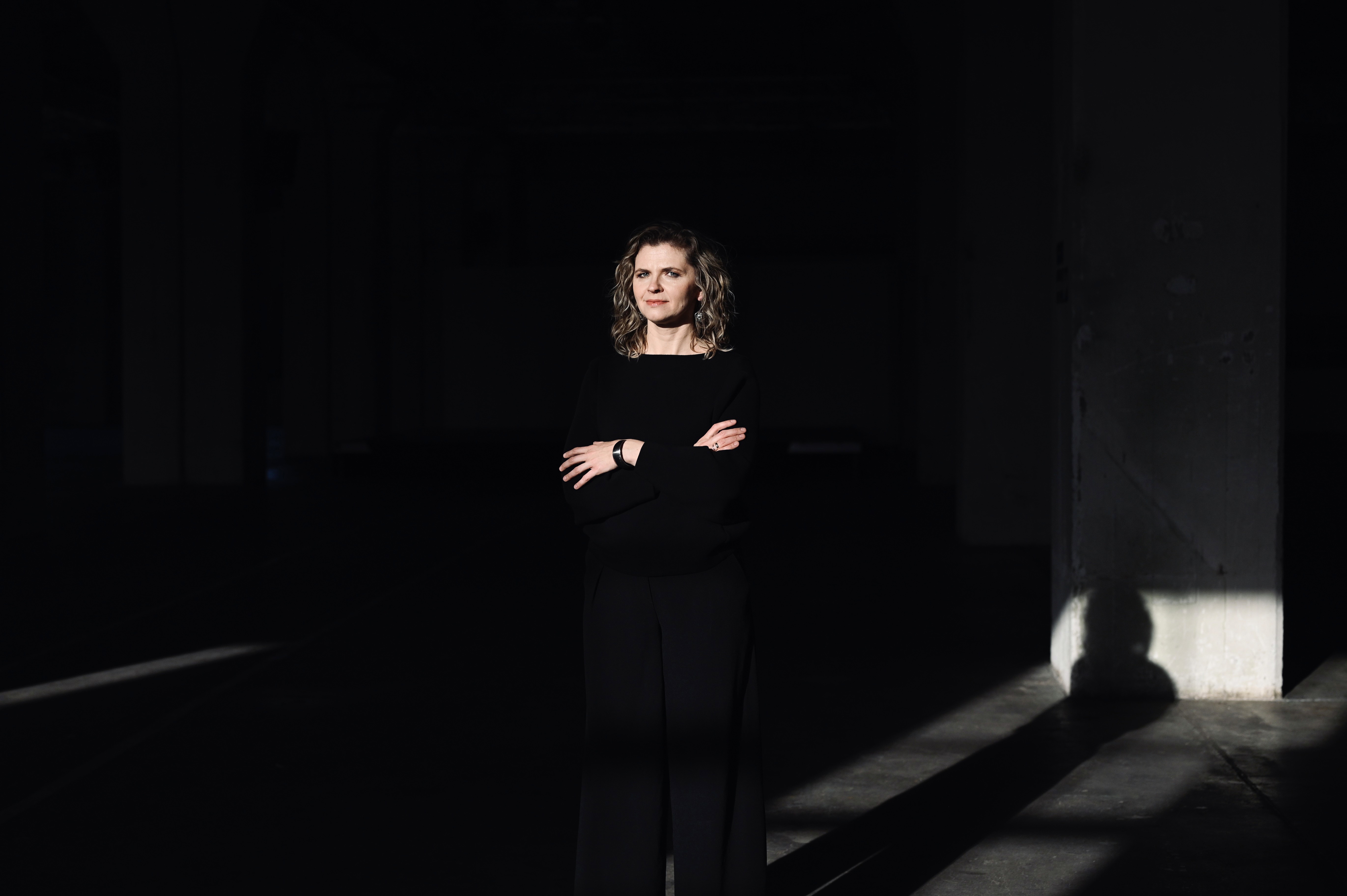 Kobieta siedząca w trawie na skraju lasu patrząca w niebo