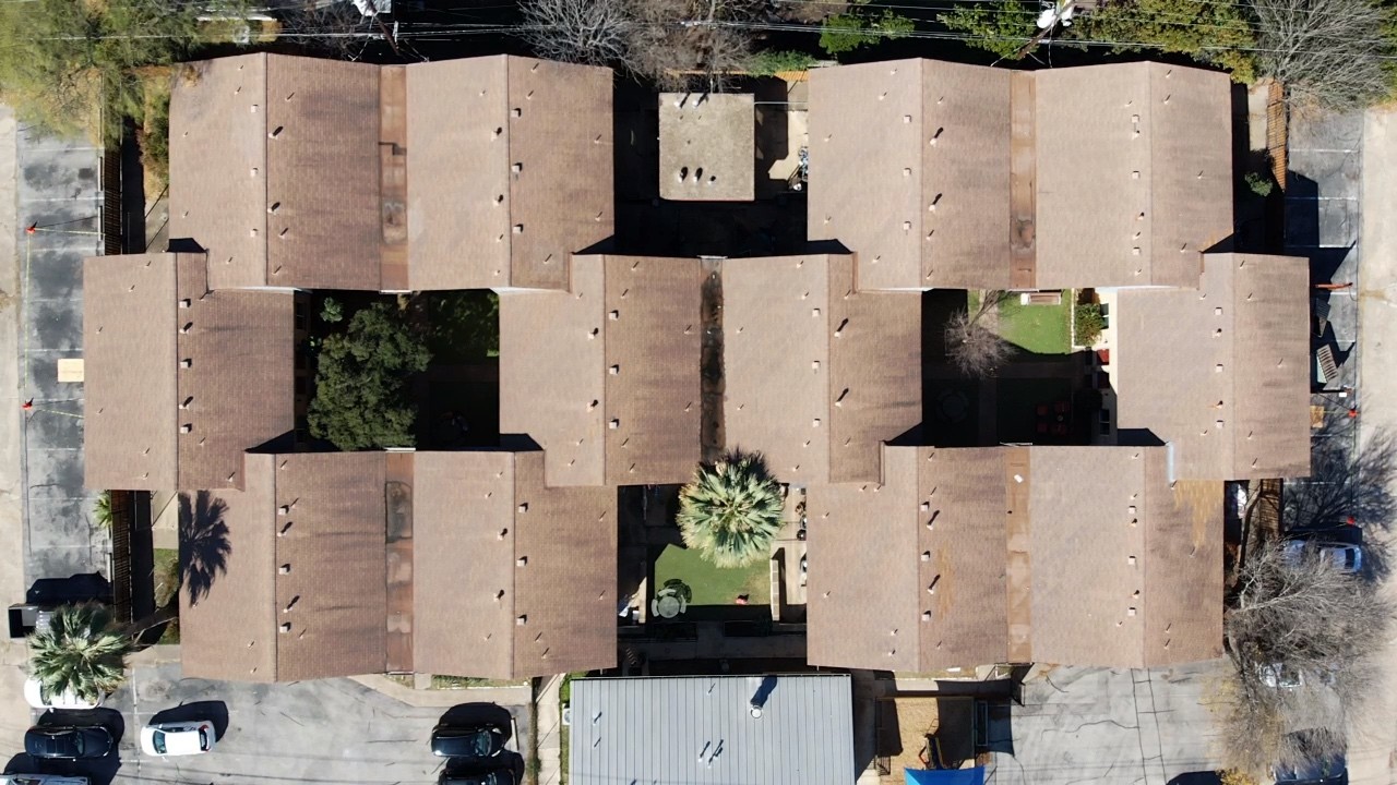 Before photo of a large apartment complex with three tab shingles. 