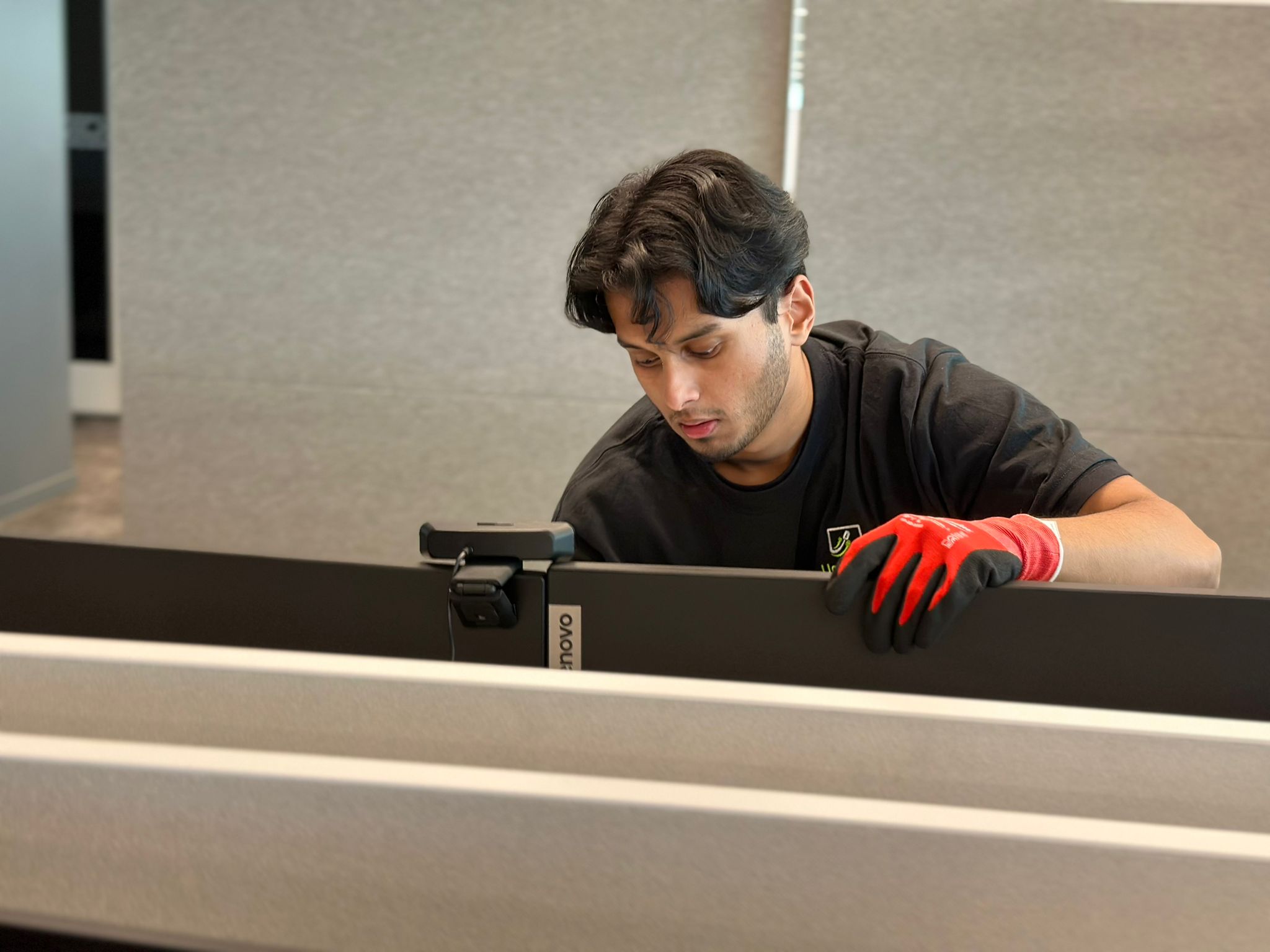 IT technician adjusting monitor and hardware setup at employee workstation
