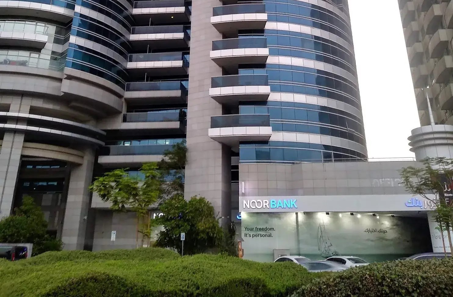 Close-up of Grosvenor Commercial Tower facade and Noor Bank branch at the base for business clients.