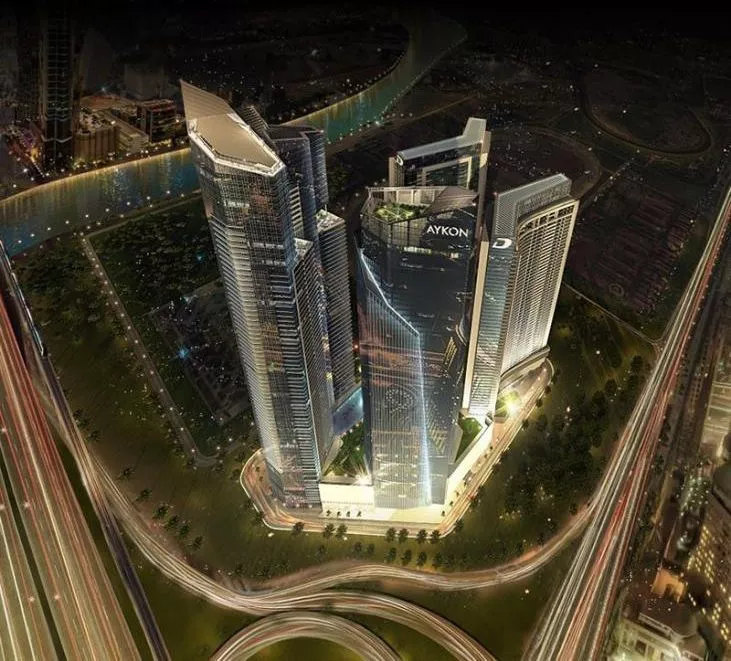 Night aerial view of Aykon City towers. Secure a luxury residence with our dedicated real estate agency services.