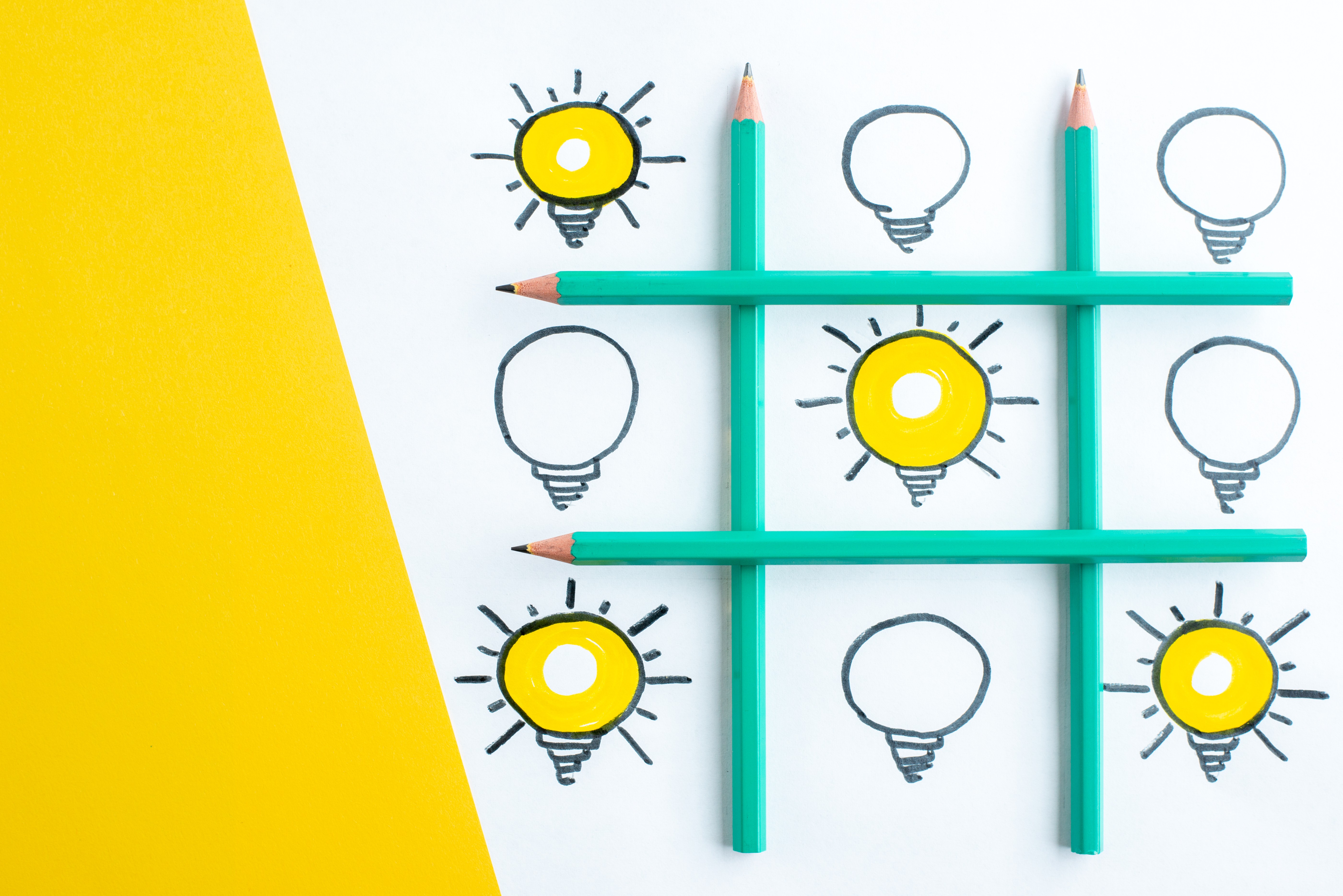 Creative concept with pencils forming a tic-tac-toe grid and lightbulbs symbolizing bright ideas and innovation