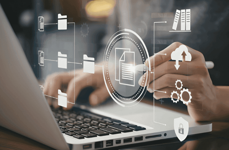 Una persona revisa gráficos y cuadros impresos mientras está sentada en un escritorio con una computadora portátil en el fondo.