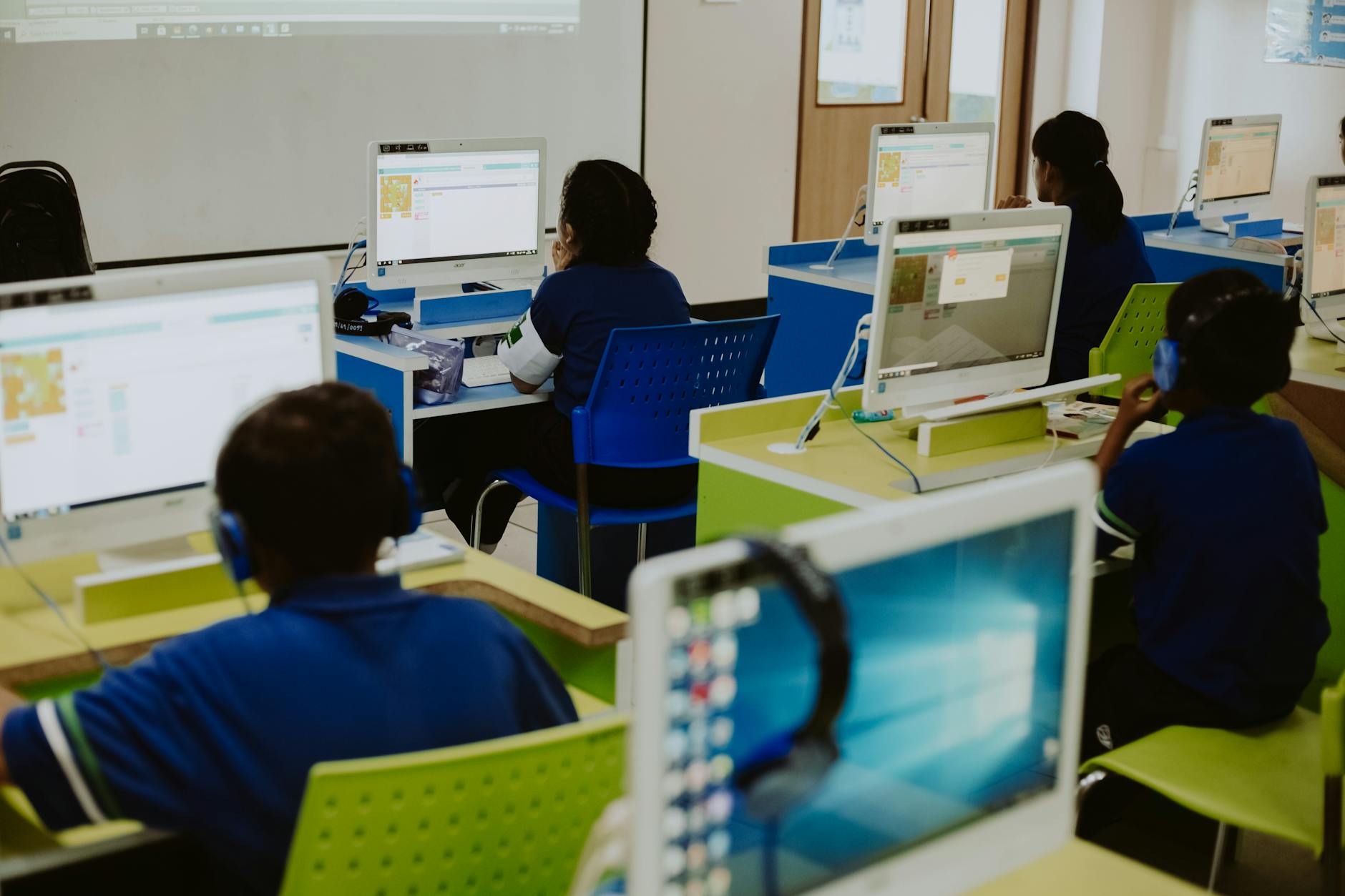 Close-up of a student's hands typing on a mechanical keyboard while looking at a coding interface on a monitor.