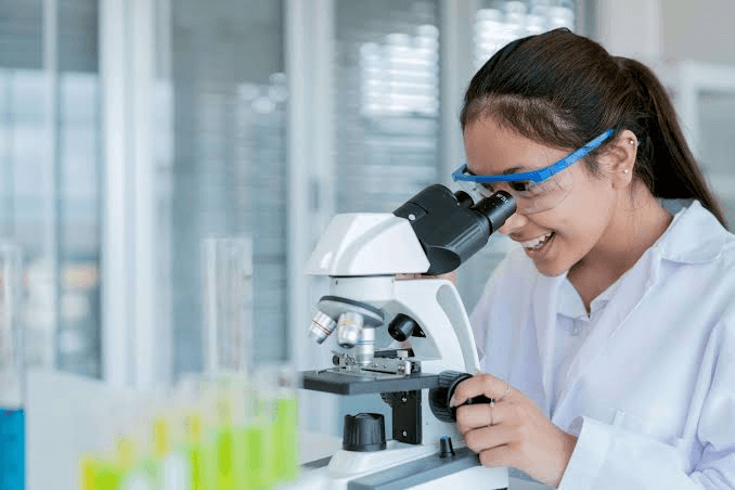 High school student working on academic research at a desk with scientific journals and a laptop