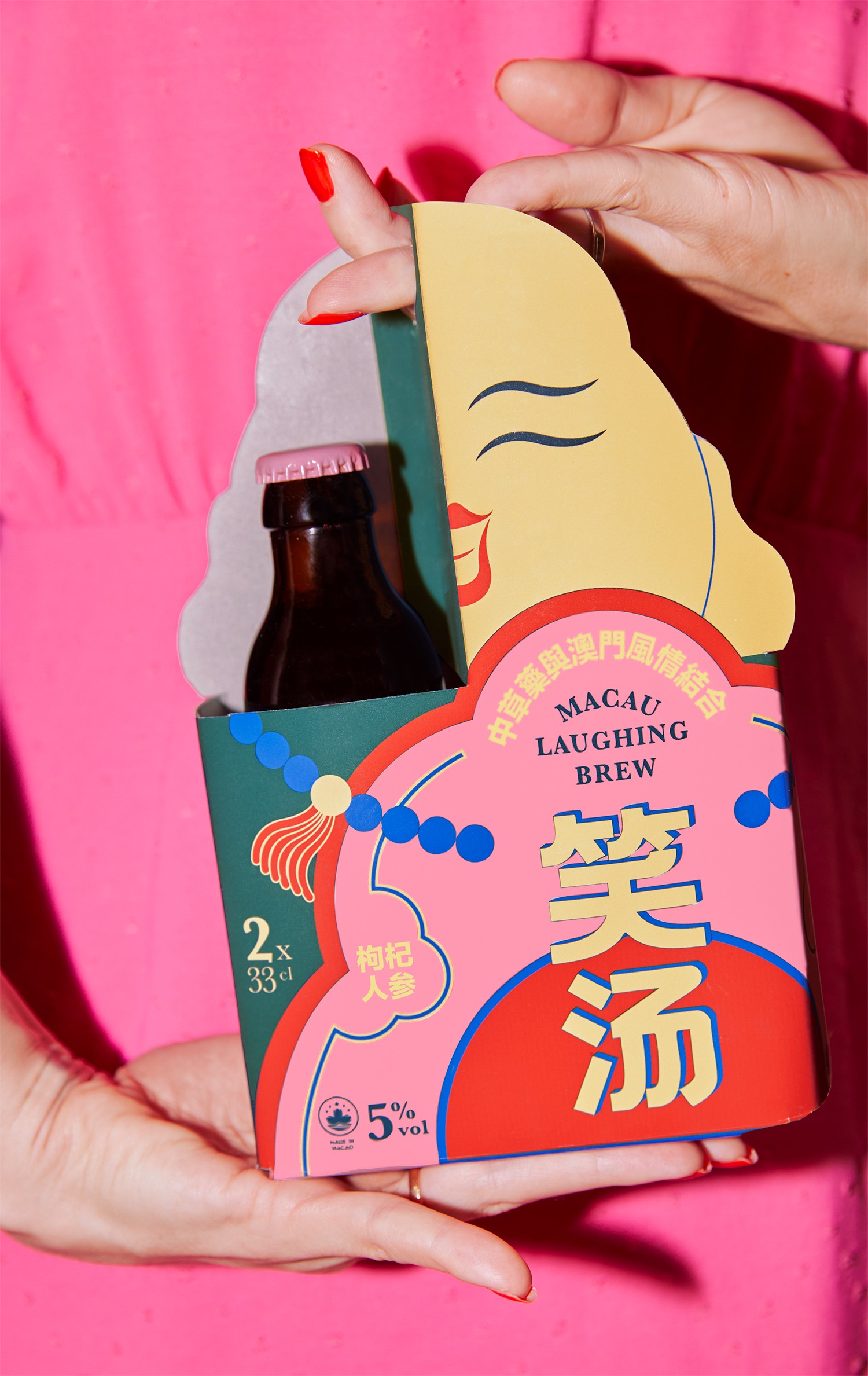 Macau Laughing Brew four pack carrier with illustrated label being held by a hand.