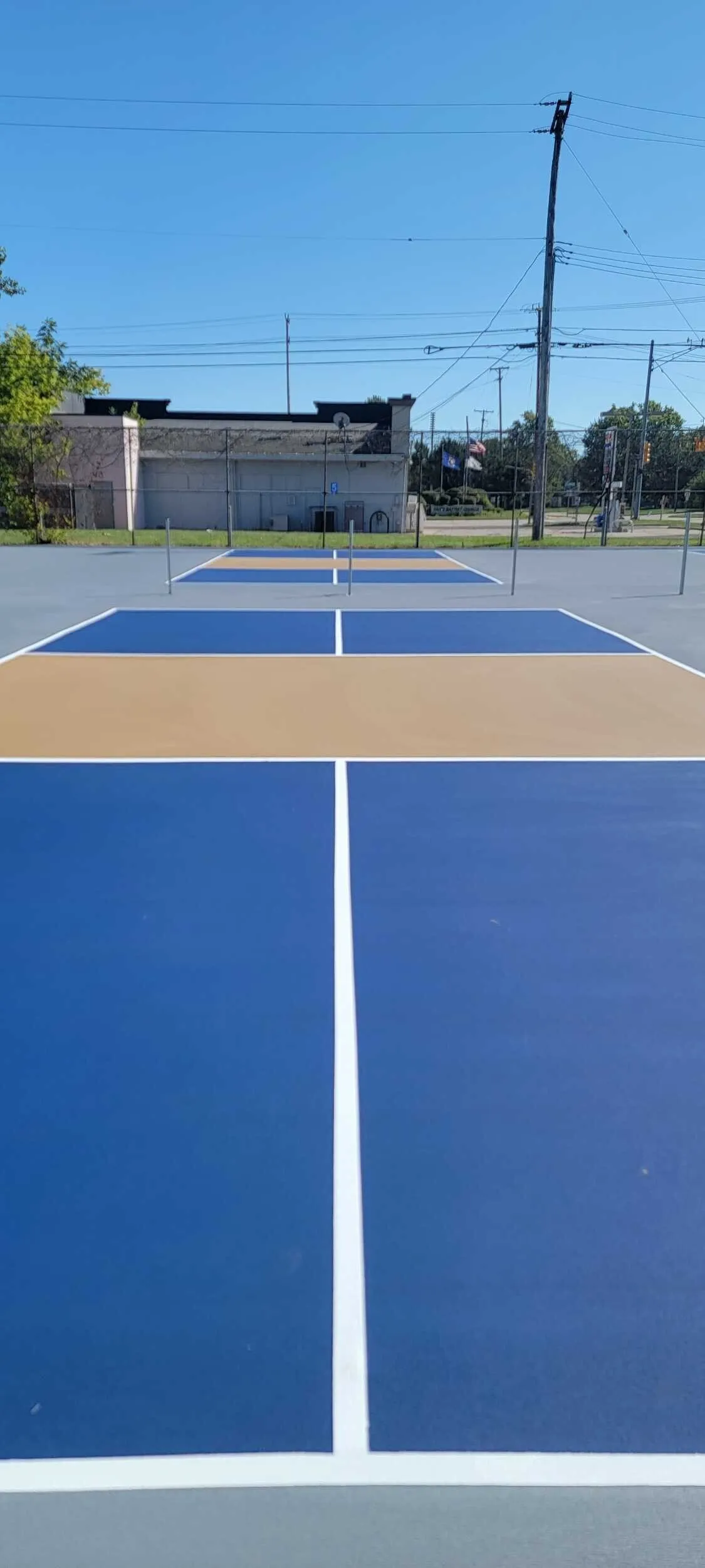 Newly resurfaced pickleball courts with blue playing areas, tan kitchens, and gray surrounds at Clintondale Community Schools