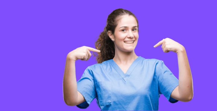 Smiling healthcare worker in scrubs pointing at herself on a purple background