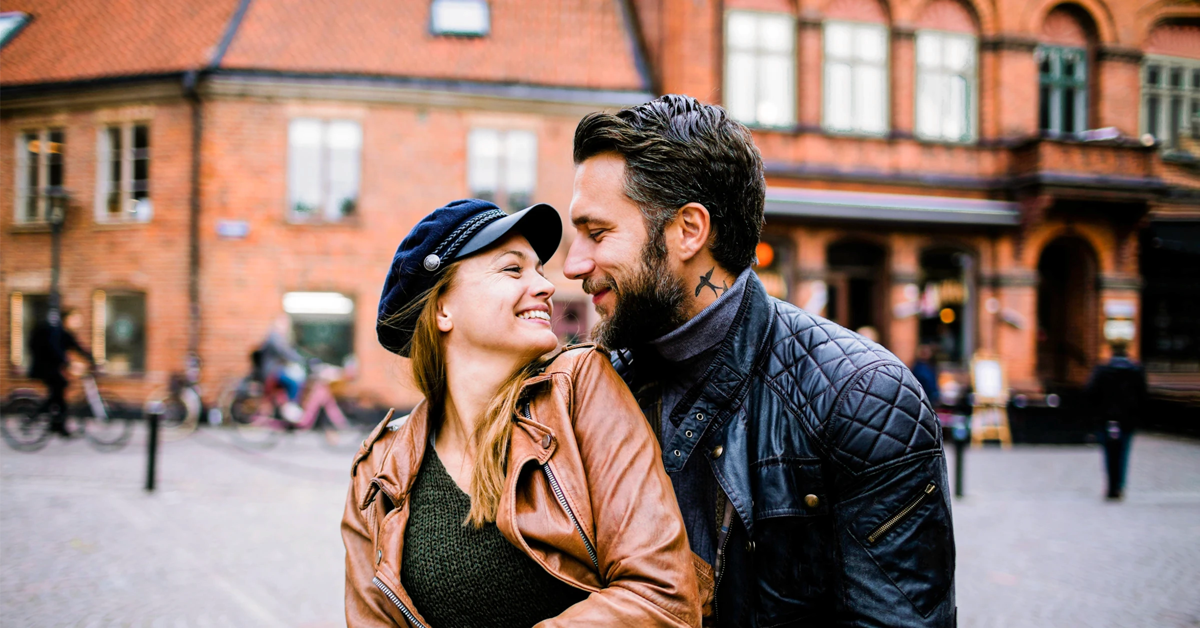 Et par, en badboy og en kvinne, ser dypt inn i hverandres øyne mens de smiler romantisk til hverandre.