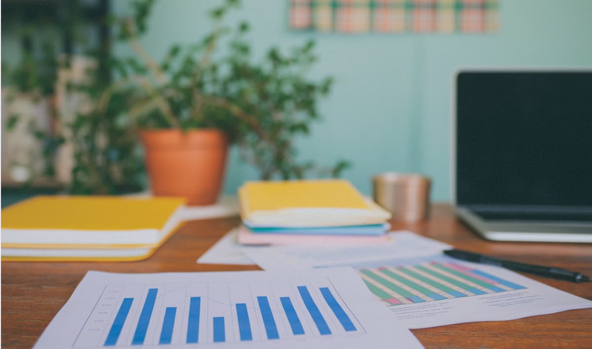 Desk with printed out bar charts and a potted plant
