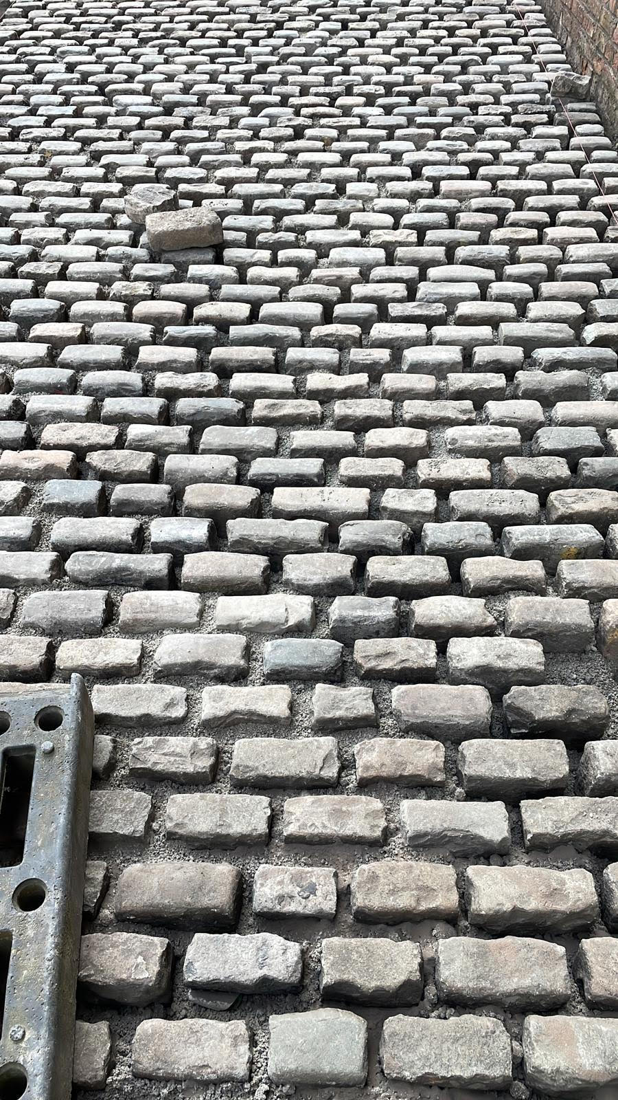 A grey cobblestone path which has been handcrafted by landscaping and groundwork techniques