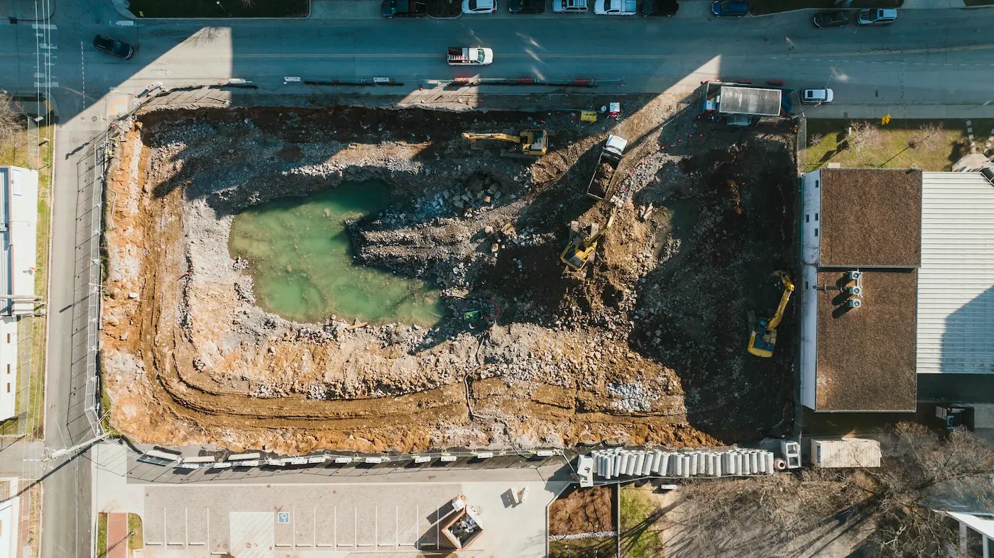 Top-down aerial photography of a construction excavation site, documenting groundworks and machinery progress