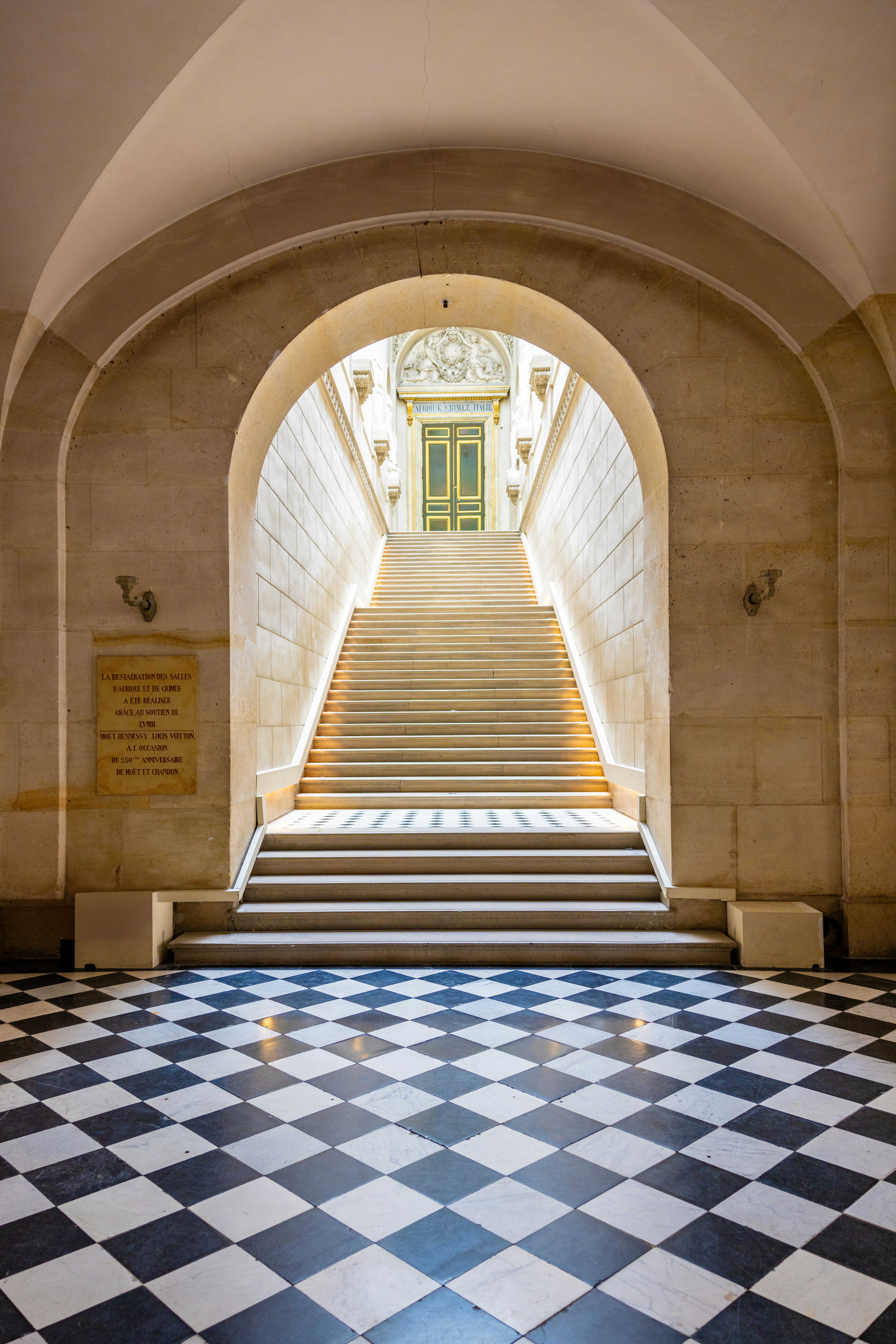 A hallway with a checkered floor and stairs