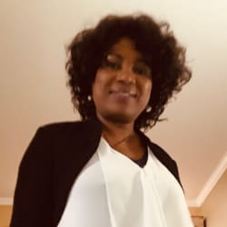 A man in a suit smiles confidently with his arms crossed, exuding professionalism and approachability.