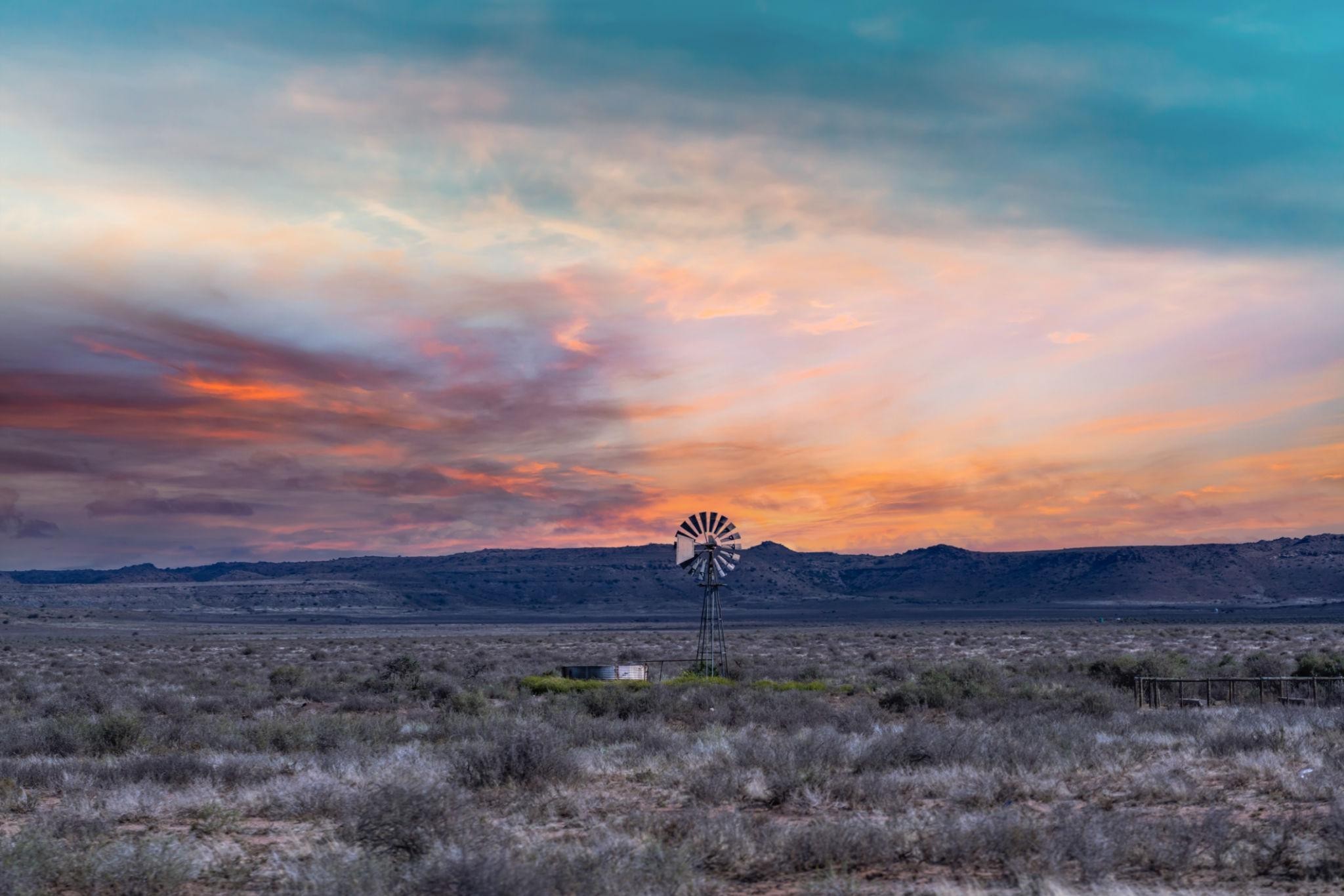Scenic view of the Karoo with mountain and clouds far away and a windmill in the middle