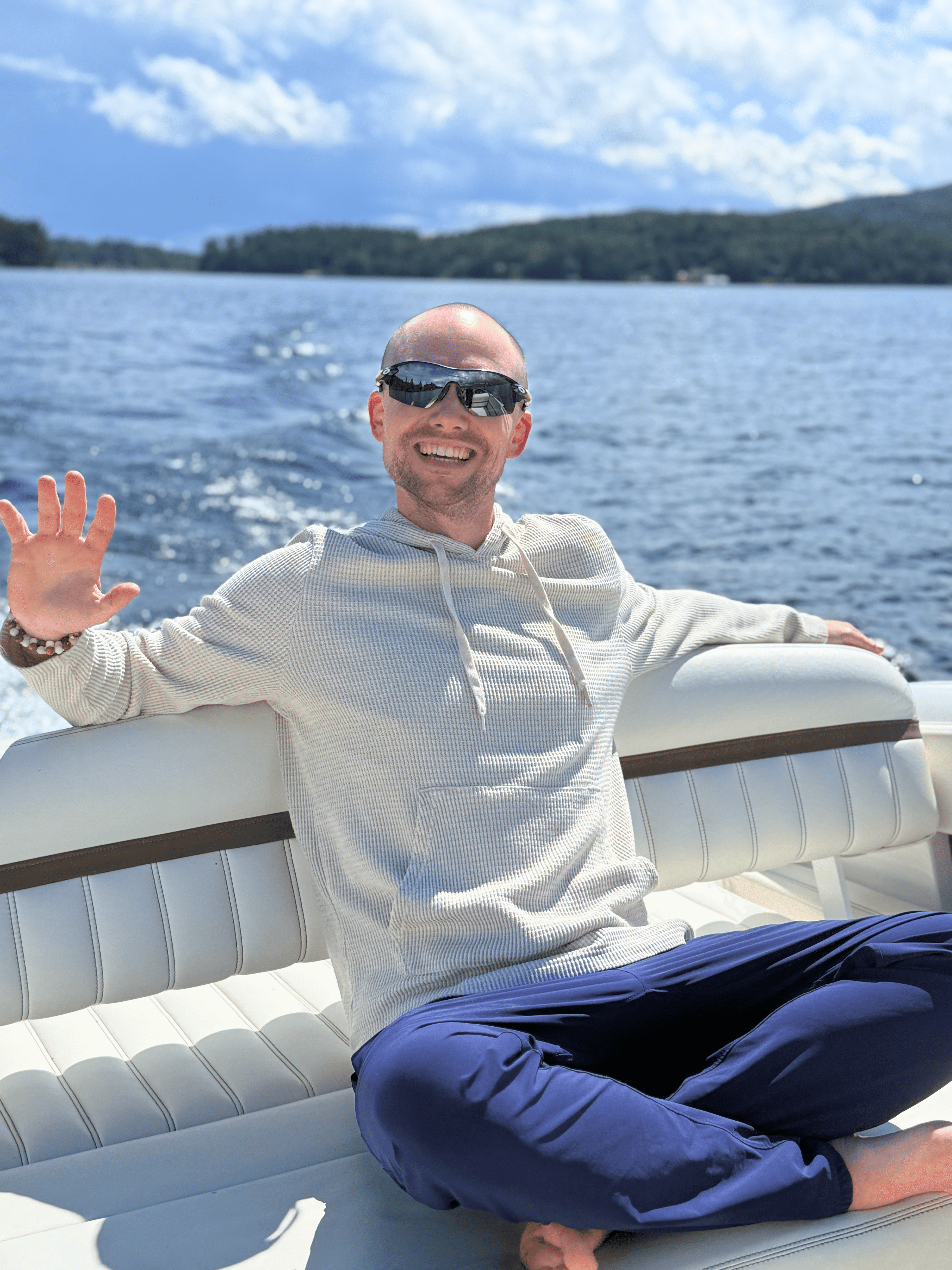 man sitting in a boat waving at the camera