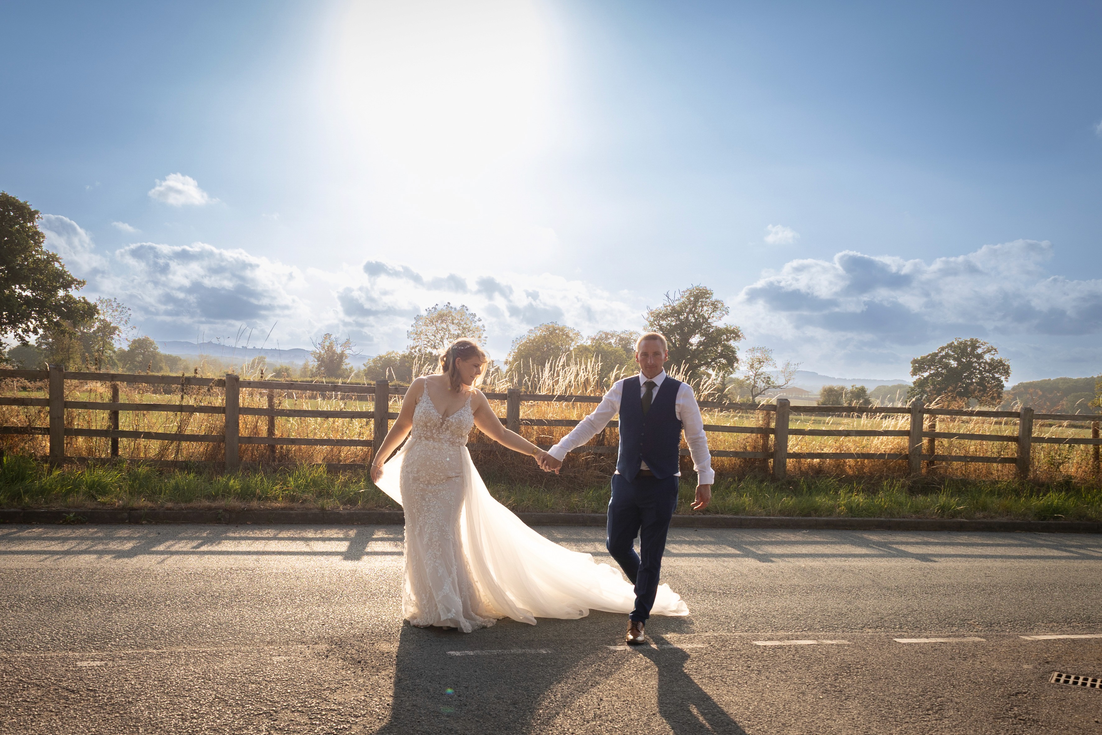 Will and Becs holding hands and walking together in warm evening light near Shrewsbury