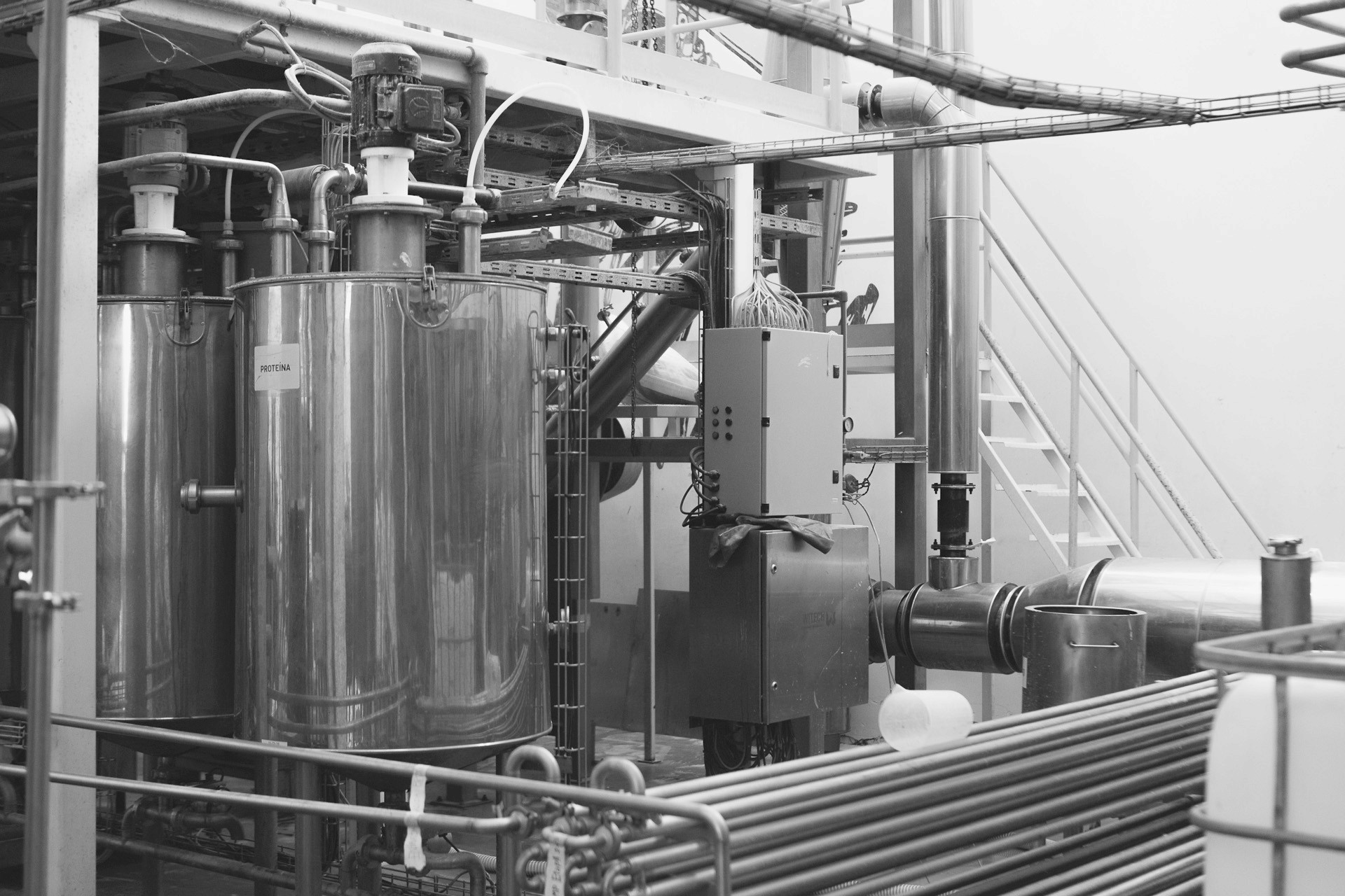 Stainless steel processing tanks and piping in an industrial food production plant.