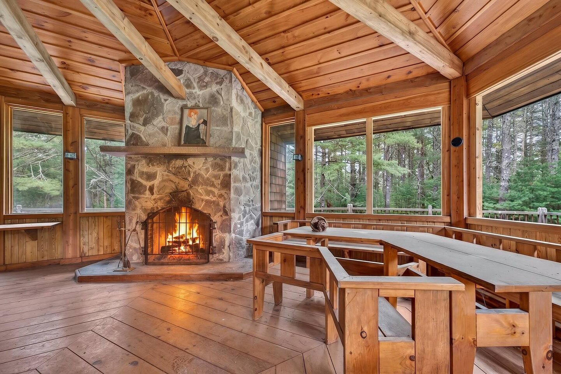 Inside the octagonal gazebo: a fieldstone fireplace, long timber tables and windows onto the pines