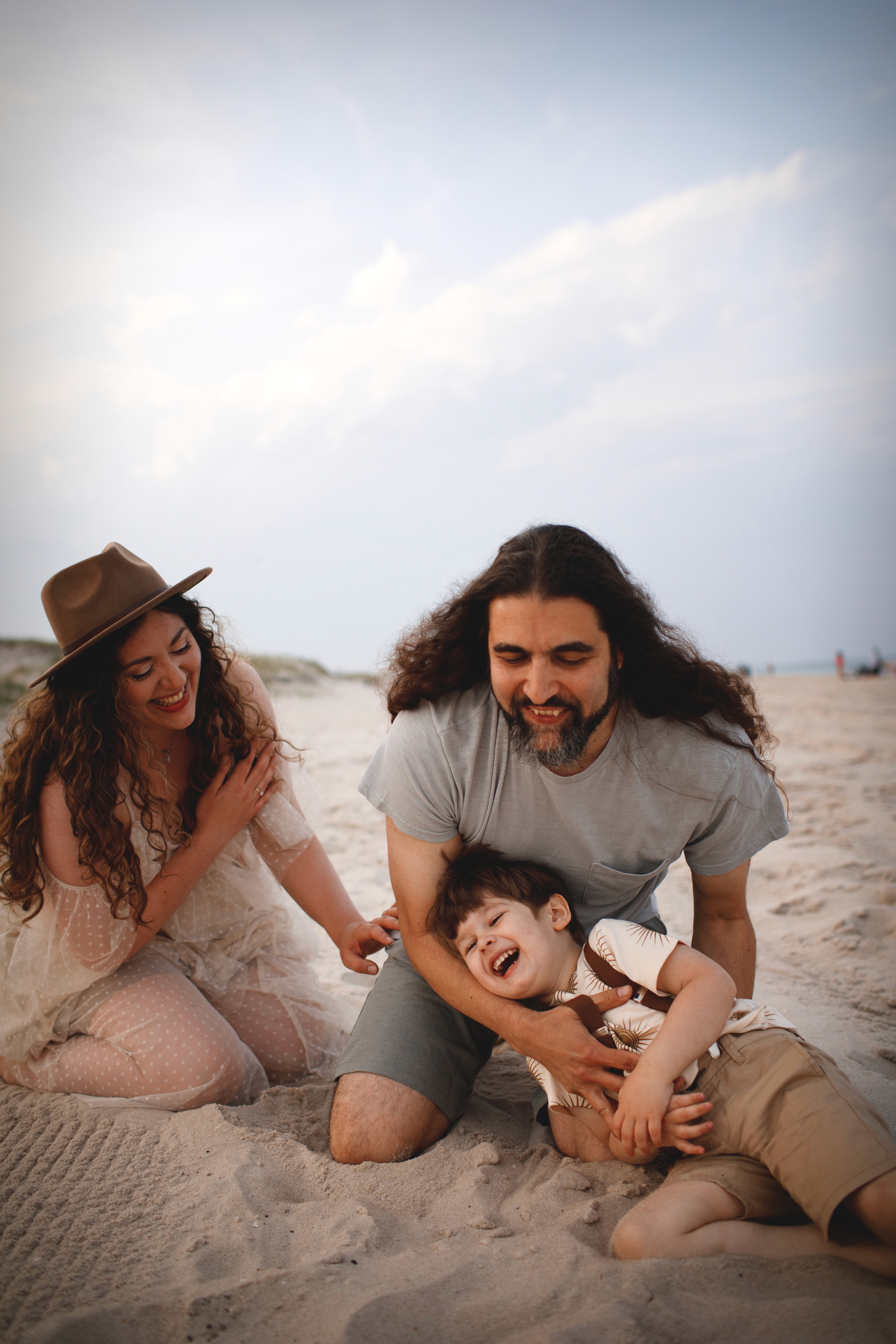 Smiling young boy lying in the sand during a playful candid family moment.