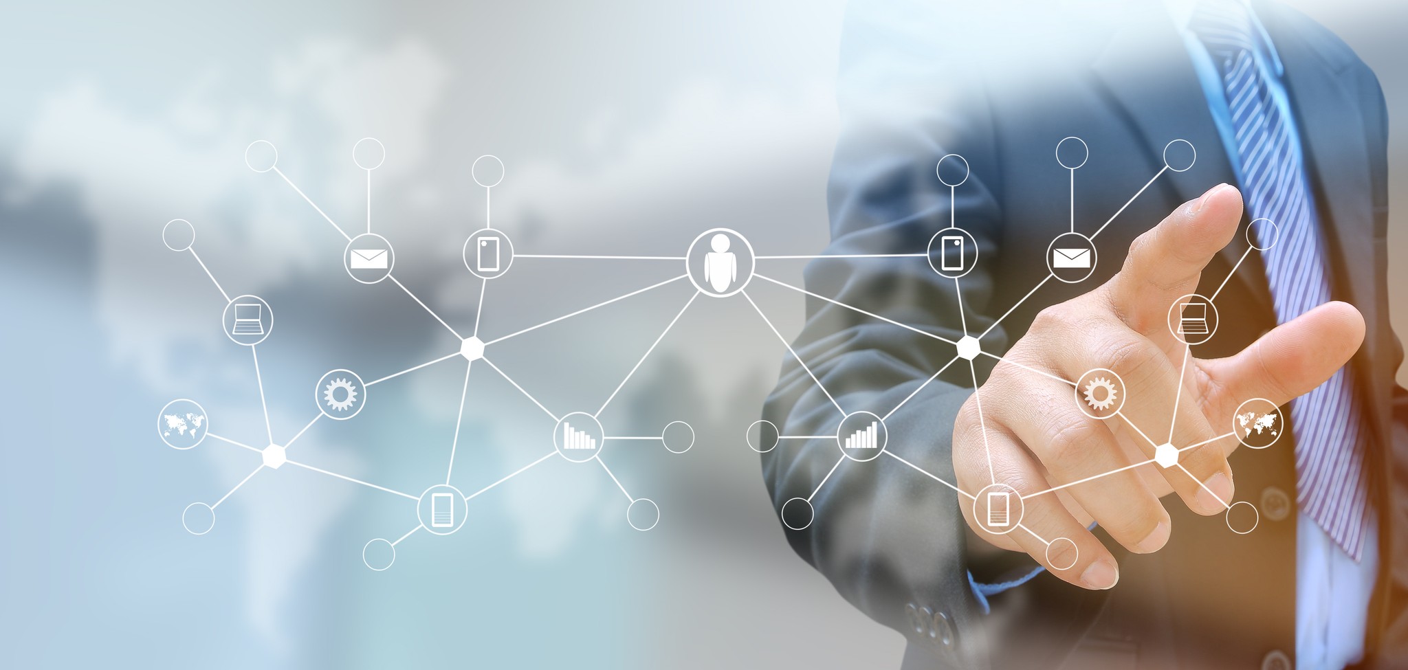 A young person with curly hair smiles at the camera while sitting in front of a laptop against a dark background.
