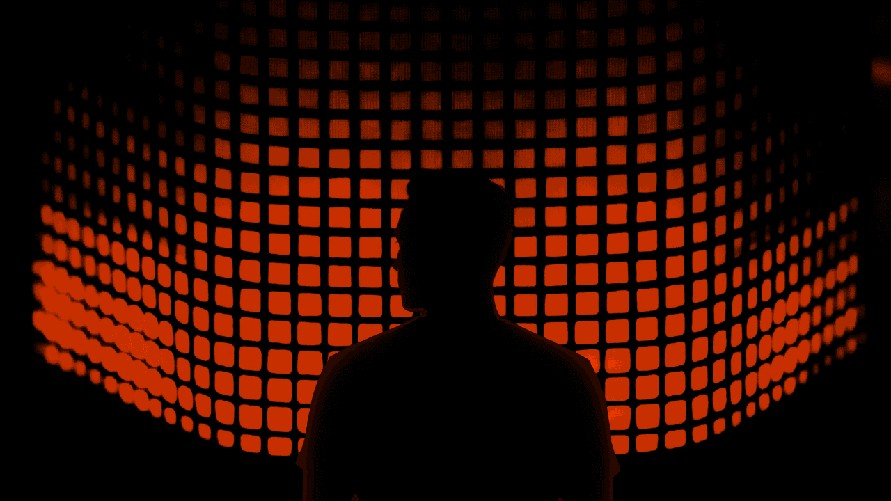 Silhouette of a person facing a large, curved grid of glowing orange squares, resembling an equalizer.