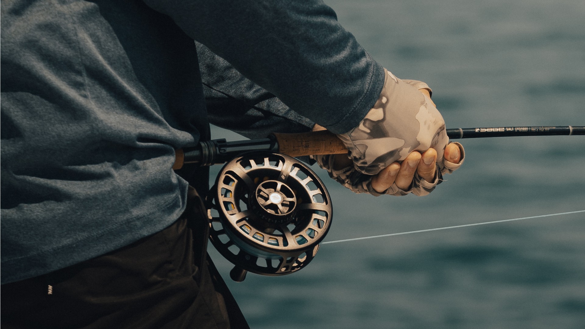 Closeup of a saltwater angler fighting a fish and pulling the fly fishing rod with both hands