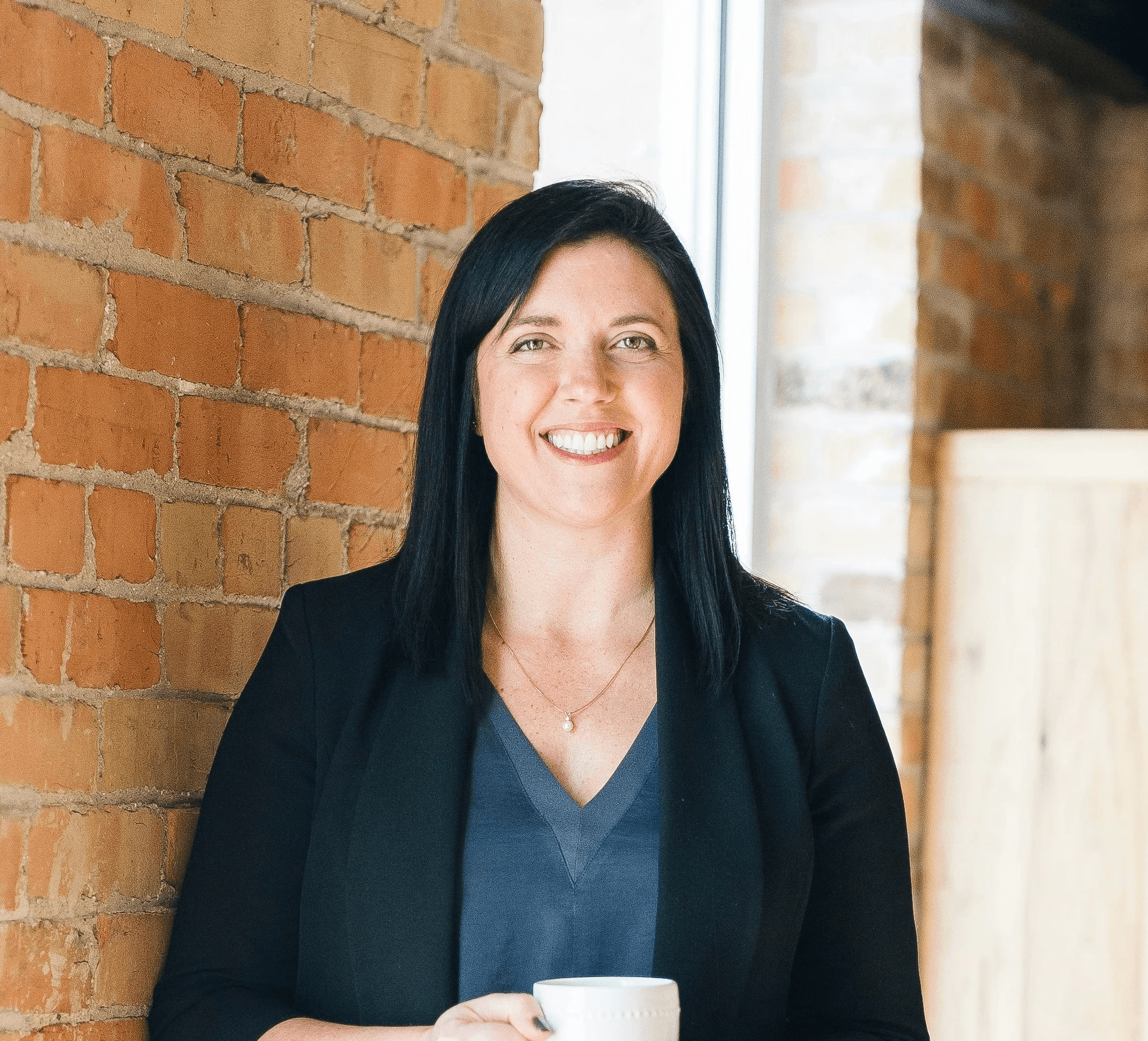 woman standing by wall holding mug