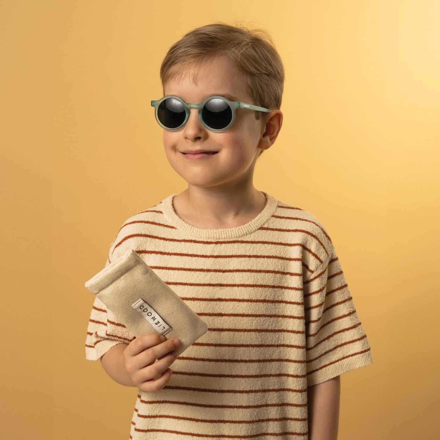 A boy wearing sunglasses on a bright yellow background