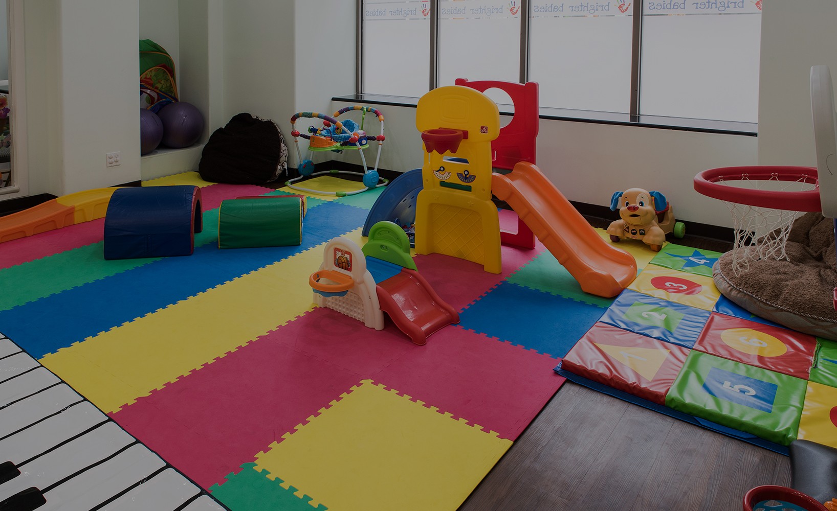 Cover image for Brighter Babies NYC featuring a colorful indoor playroom with soft mats, slides, and toys at Brighter Babies Early Development Center.