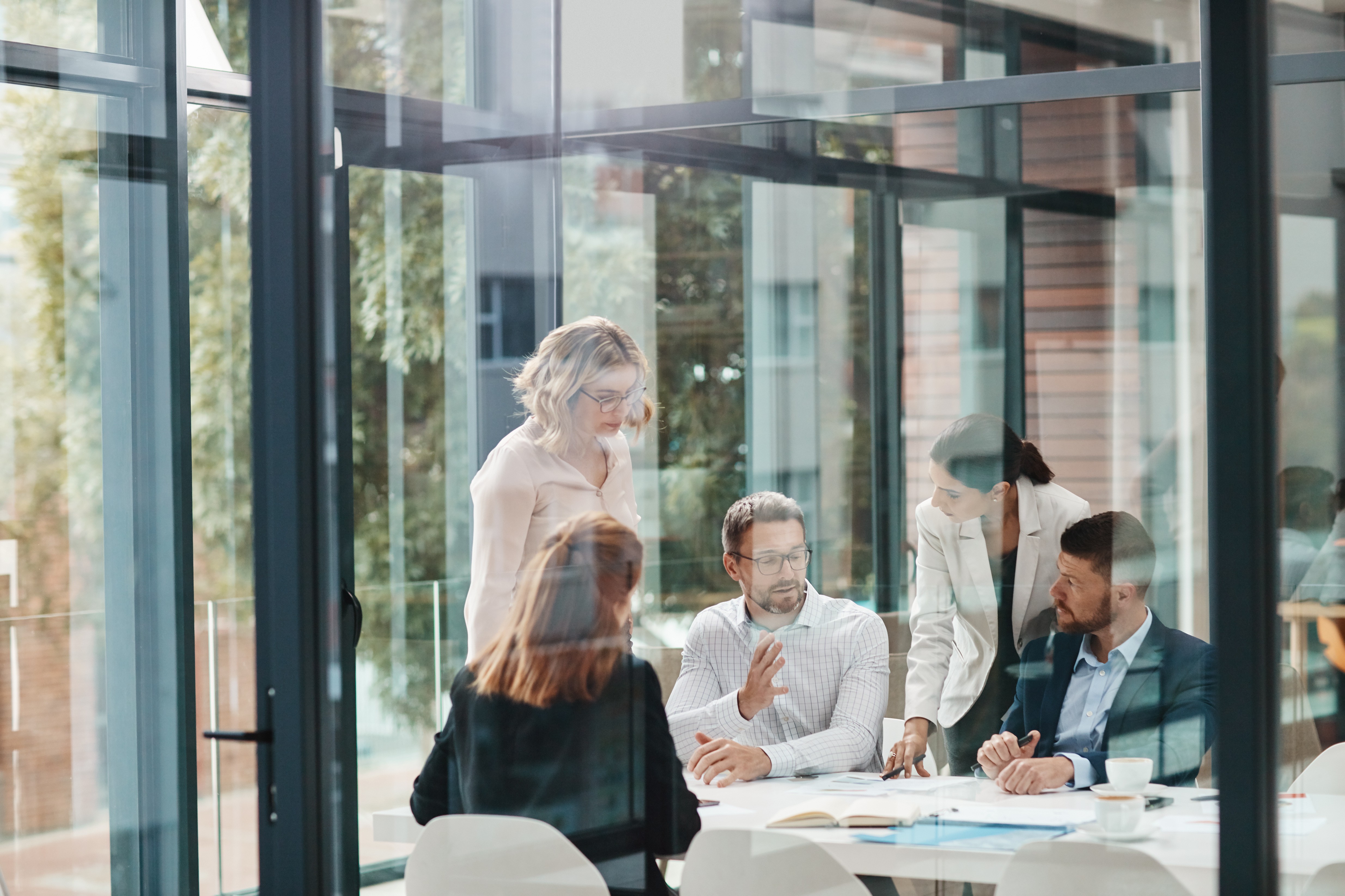 Professionals collaborating in a meeting room, representing role-specific professional tracks for building, operating, and auditing management systems.
